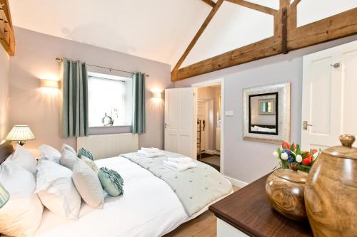 a bedroom with a large white bed and a table at Juniper Cottage in Bakewell