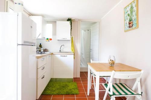 una cocina con armarios blancos y una mesa con una alfombra verde en Villa Aurelia - Modern Seafront Studio Apartment, en Flumini di Quartu