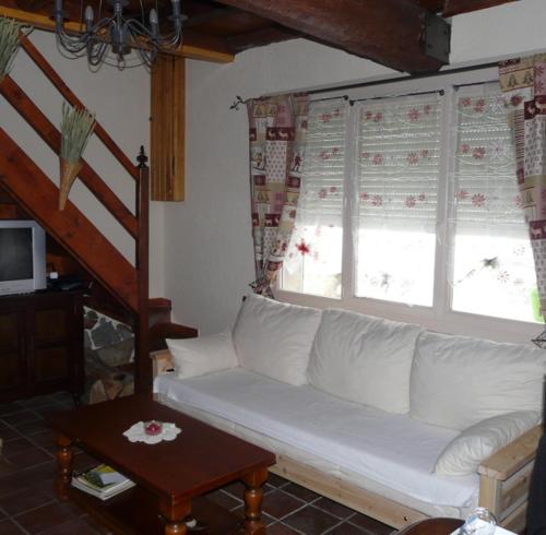 a living room with a white couch and two windows at Oustals De Lavail in Ascou