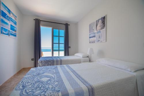 a bedroom with two beds and a view of the ocean at Residencial Arena del Sol 6 by Olax Rentals in Puerto de Santiago