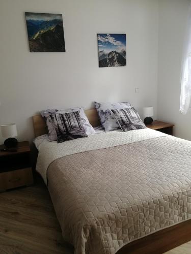 a bed in a bedroom with two pictures on the wall at Apartament Klimek in Białka Tatrzańska