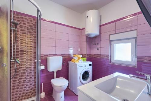 y baño rosa con aseo y lavadora. en Apartman Modry en Pula