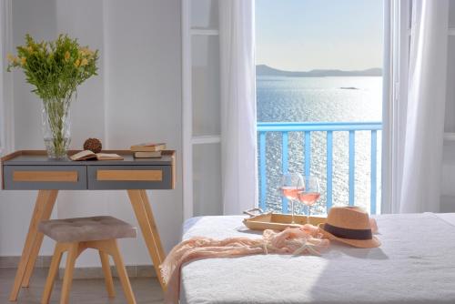 a bedroom with a table and a view of the ocean at Amelie Suites in Agios Stefanos