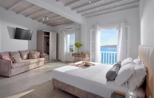a white bedroom with a large bed and a couch at Amelie Suites in Agios Stefanos