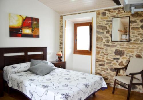 a bedroom with a bed and a stone wall at Fogar de Insua in Touro