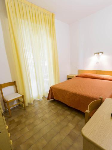 a bedroom with a bed and a chair and a window at Hotel Meris in Milano Marittima