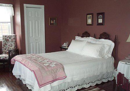 a bedroom with a bed with a pink wall at Argyle By The Sea Bed & Breakfast in Pubnico