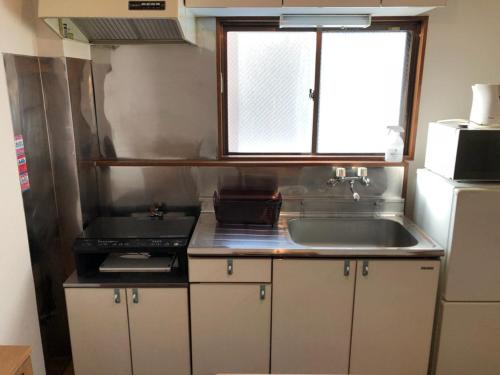 una pequeña cocina con fregadero y ventana en First Hongo Building 202 / Vacation STAY 3355, en Chiba