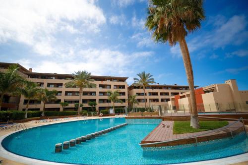 une grande piscine avec un palmier et des bâtiments dans l'établissement Spacious and comfortable Paraiso II, à Playa Paraiso