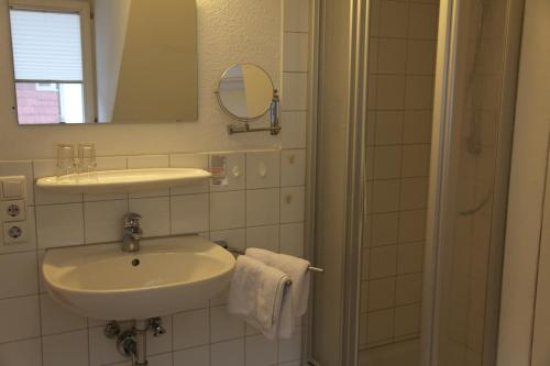 een witte badkamer met een wastafel en een douche bij Hotel Bacchus Wine & Bites in Meersburg