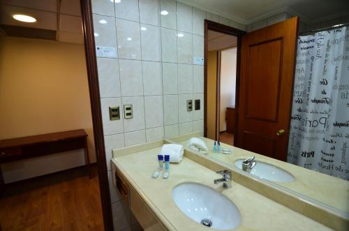 a bathroom with two sinks and a large mirror at Tur Hotel Santiago in Santiago