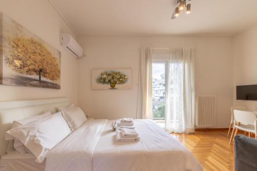 a bedroom with a white bed and a window at Top sightseeing 3rd floor studio on a paved road! in Athens