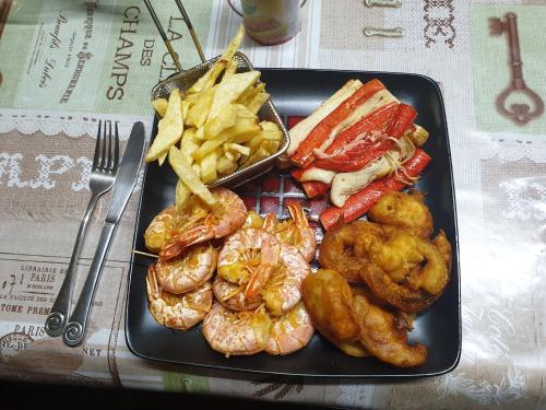 a black plate of food with shrimp and french fries at The Haven: Make our Home your Home in Estcourt