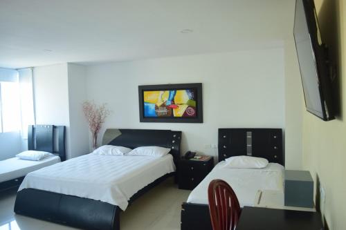 a bedroom with two beds and a tv on the wall at Hotel Intersuites in Barranquilla