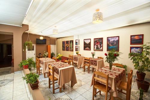 ein Restaurant mit Tischen, Stühlen und Gemälden an den Wänden in der Unterkunft Hostal Danna Inn in Cusco