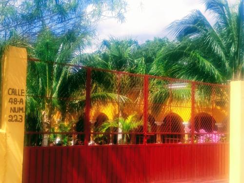 a red fence with palm trees in the background at Casa Palagui Colonial in Valladolid