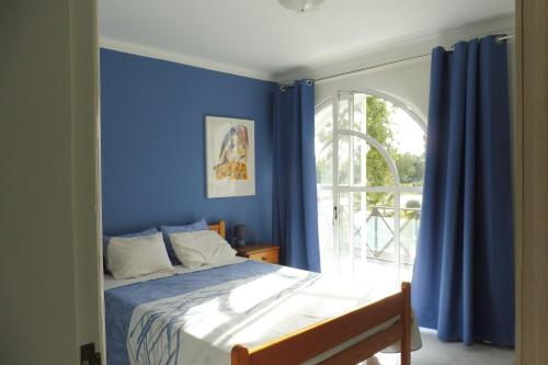 a bedroom with blue walls and a bed with a window at Holiday in the Algarve - Tavira Garden T1 in Tavira