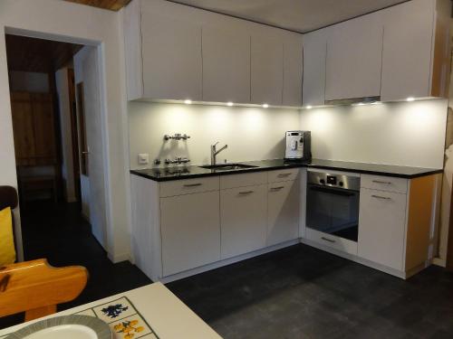 a small kitchen with white cabinets and a sink at Haus Primula Pizol in Wangs