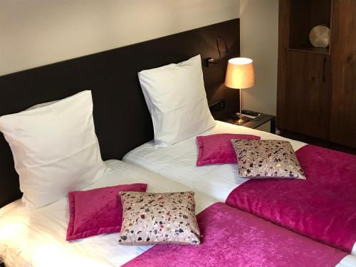 a bedroom with two beds with pink sheets and pillows at Hôtel L'Auberge Alsacienne in Eguisheim