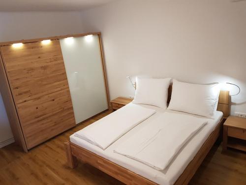 a bedroom with a white bed with a wooden door at Seesuiten Mörbisch in Mörbisch am See