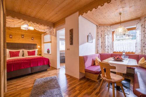 Schlafzimmer mit einem roten Bett, einem Tisch und Stühlen in der Unterkunft Appartements Enzian in Finkenberg