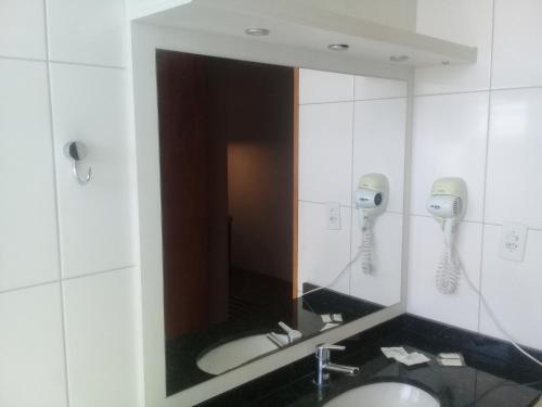 Canoas Parque Hotel في كانواس: مرآة في الحمام مع مغسلتين وهاتف