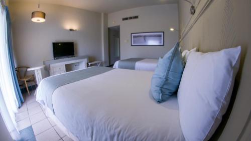 sypialnia z dużym białym łóżkiem z niebieskimi poduszkami w obiekcie Club Maeva Miramar Tampico w mieście Ciudad Madero
