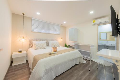 a bedroom with a bed and a desk and a television at Medellín Vibes Hostel in Medellín