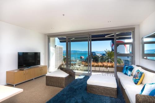 Una sala de estar con un sofá blanco y un televisor. en Latitude Waterfront Apartment, en Nelson