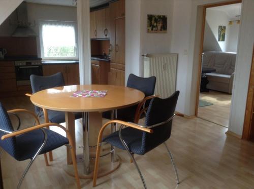 una mesa de madera y sillas en una cocina con mesa en Ferienwohnungen am Schwanenteich, en Mühlhausen