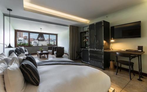 a bedroom with a large white bed and a desk at The Charlee Hotel in Medellín