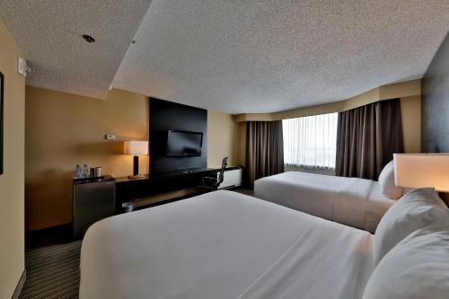 a hotel room with two beds and a television at Edmonton Hotel & Convention Center Edmonton in Edmonton