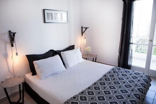 a bedroom with a bed with white sheets and a window at Best located executive apartment in Maroussi. in Athens