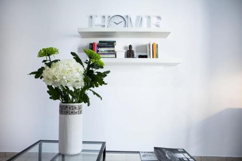 a vase with white flowers sitting on a glass table at Best located executive apartment in Maroussi. in Athens