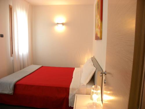 a bedroom with a red and white bed and a lamp at Venice Apartments Dante in Mestre