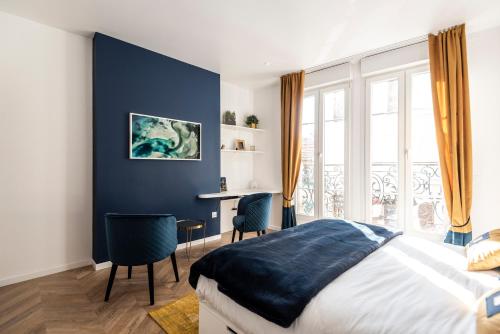 Schlafzimmer mit blauen Wänden, einem Bett und einem Schreibtisch in der Unterkunft MM Suites Marlot in Reims