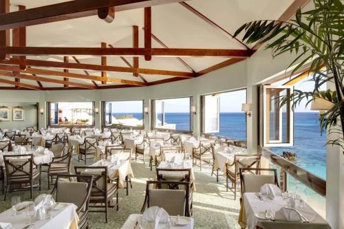 a restaurant with tables and chairs with the ocean in the background at The Reefs Resort and Club in Southampton
