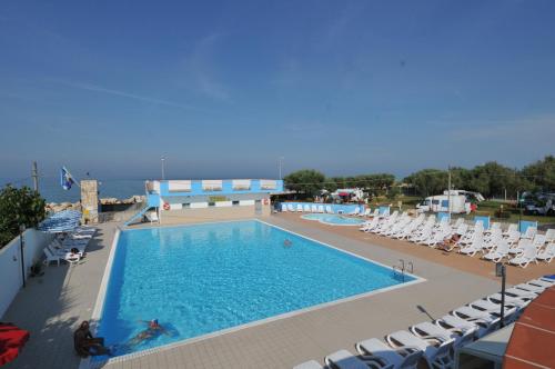 a swimming pool with chairs and the ocean in the background at EurCamping Roseto Concept Glamping in Roseto degli Abruzzi