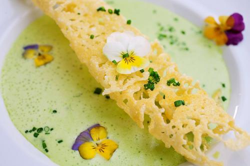 a white bowl of soup with two pieces of bread with flowers on it at Biohotel Walserstuba in Riezlern