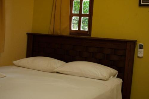 a bed with two pillows in a bedroom with a window at Pousada Casa da Gente in Caruaru