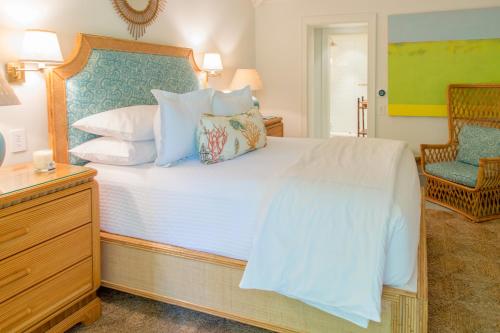 a bedroom with a large white bed and a chair at Eleven Bahama House in Harbour Island