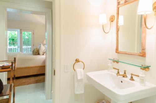 a bathroom with a sink and a mirror and a bed at Eleven Bahama House in Harbour Island