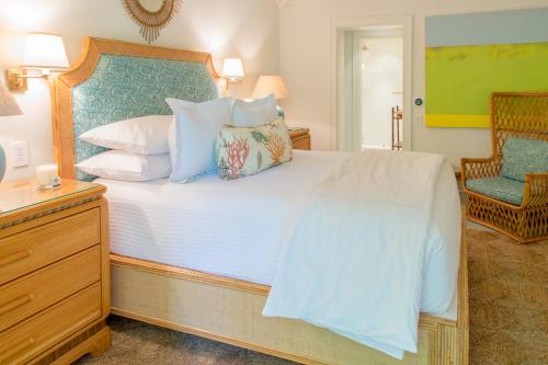 a bedroom with a large white bed and a chair at Eleven Bahama House in Harbour Island
