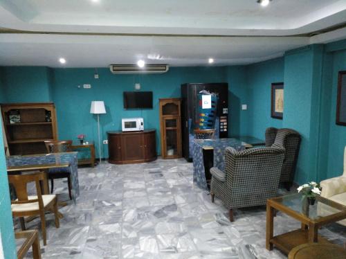 una sala de estar con paredes azules, mesas y sillas en Hotel Nuevo Ara, en Cáceres