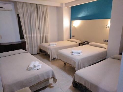 a hotel room with three beds and a blue ceiling at Hotel Nuevo Ara in Cáceres
