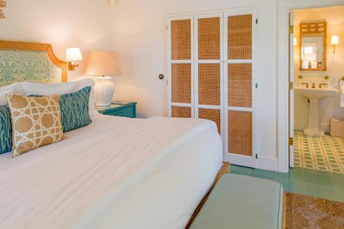 a bedroom with a white bed and a bathroom at Eleven Bahama House in Harbour Island