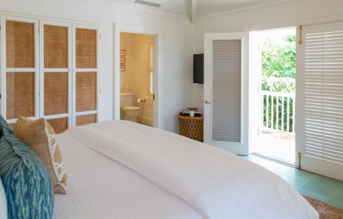 a white bedroom with a bed and a bathroom at Eleven Bahama House in Harbour Island