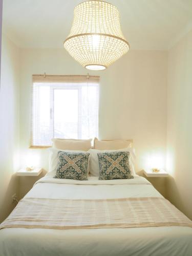 a bedroom with a large white bed with a chandelier at Pé N'Areia - Beach Apartment with Terrace in Viana do Castelo