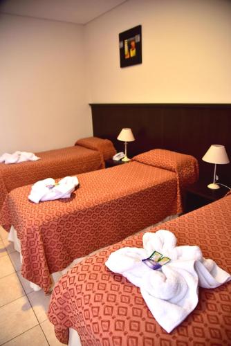 a hotel room with three beds with towels on them at Hotel Confianza in Corrientes