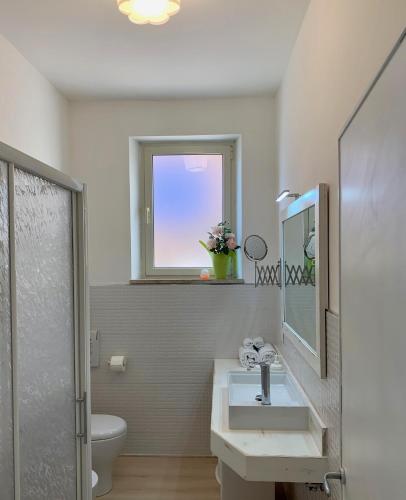 a bathroom with a sink and a toilet and a window at Casa Francesco in Bolsena
